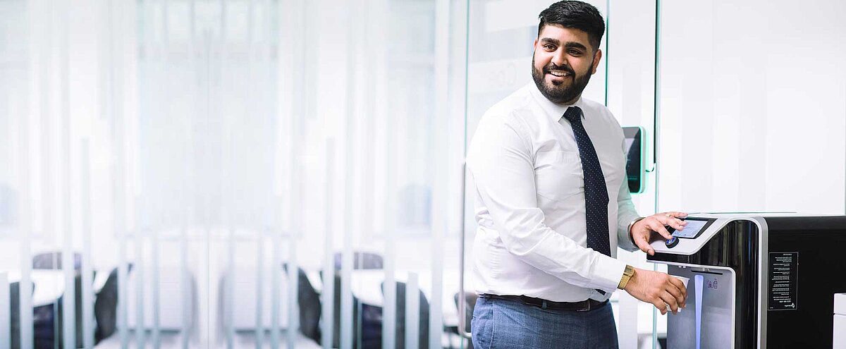 Mitarbeiter im Büro füllt sein Glas mit Wasser aus einem Waterlogic Wasserspender